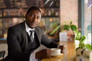 Handsome bearded African businessman relaxing inside the coffee shop